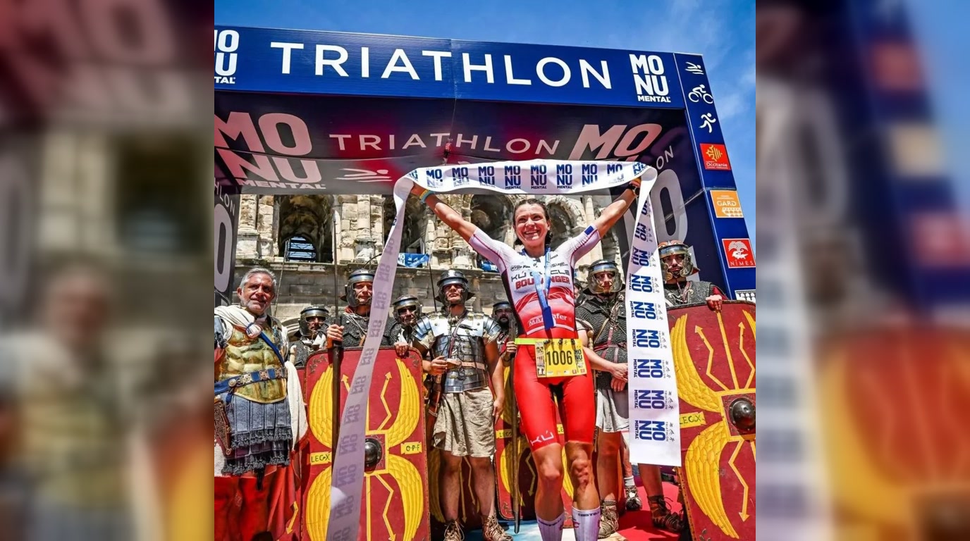 Aurélia Boulanger franchit l'arrivée du Triathlon Monumental Nîmes Pont du Gard avec la banderole de finisher