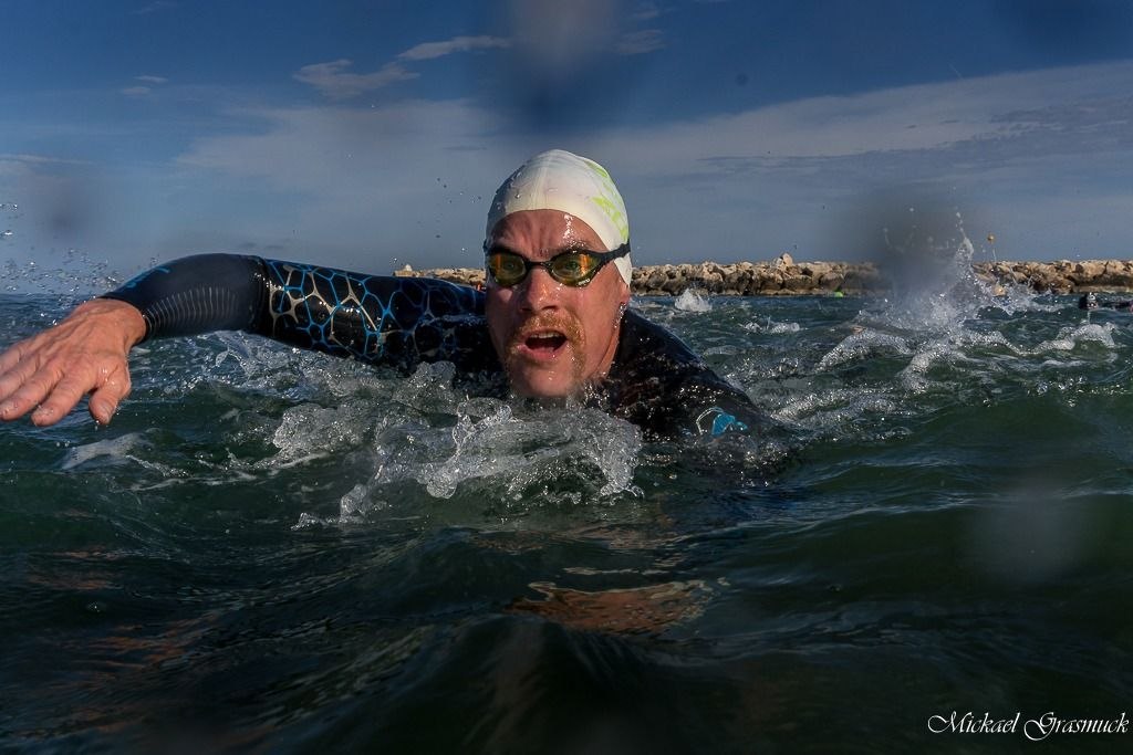 Triathlète en eau libre pendant une séance de natation, photo utilisée pour illustrer la charge d’entraînement longue distance