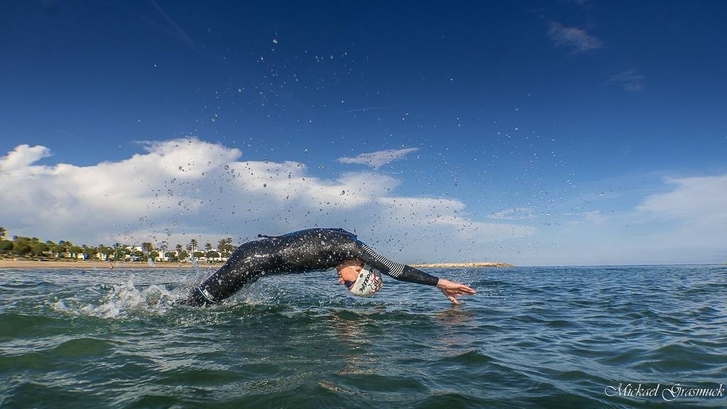 Triathlète en eau libre avec bonnet de natation, utilisé pour illustrer la décision matériel avant une course