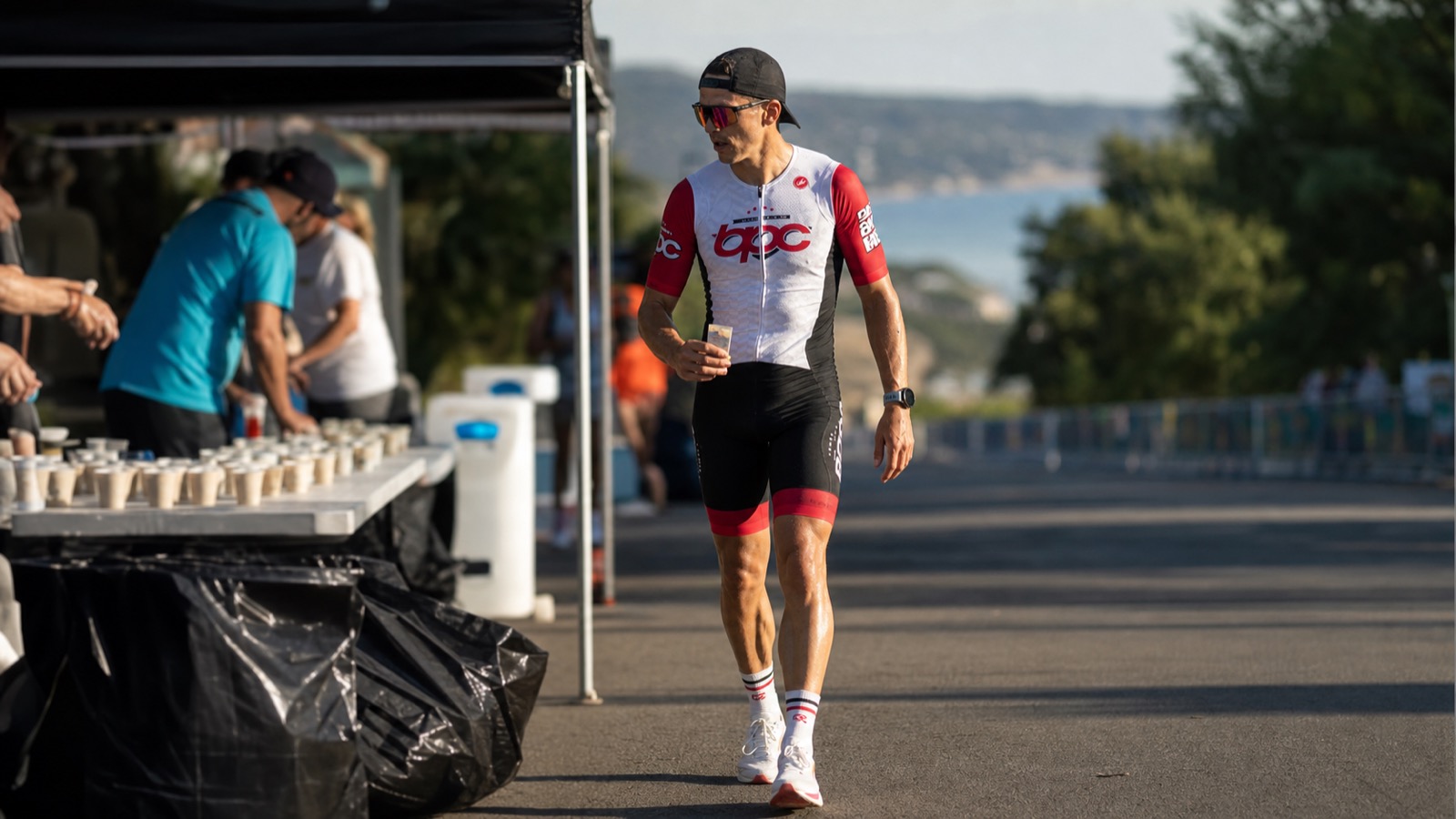 Triathlète BPC marchant près d'un ravitaillement pendant un marathon longue distance.